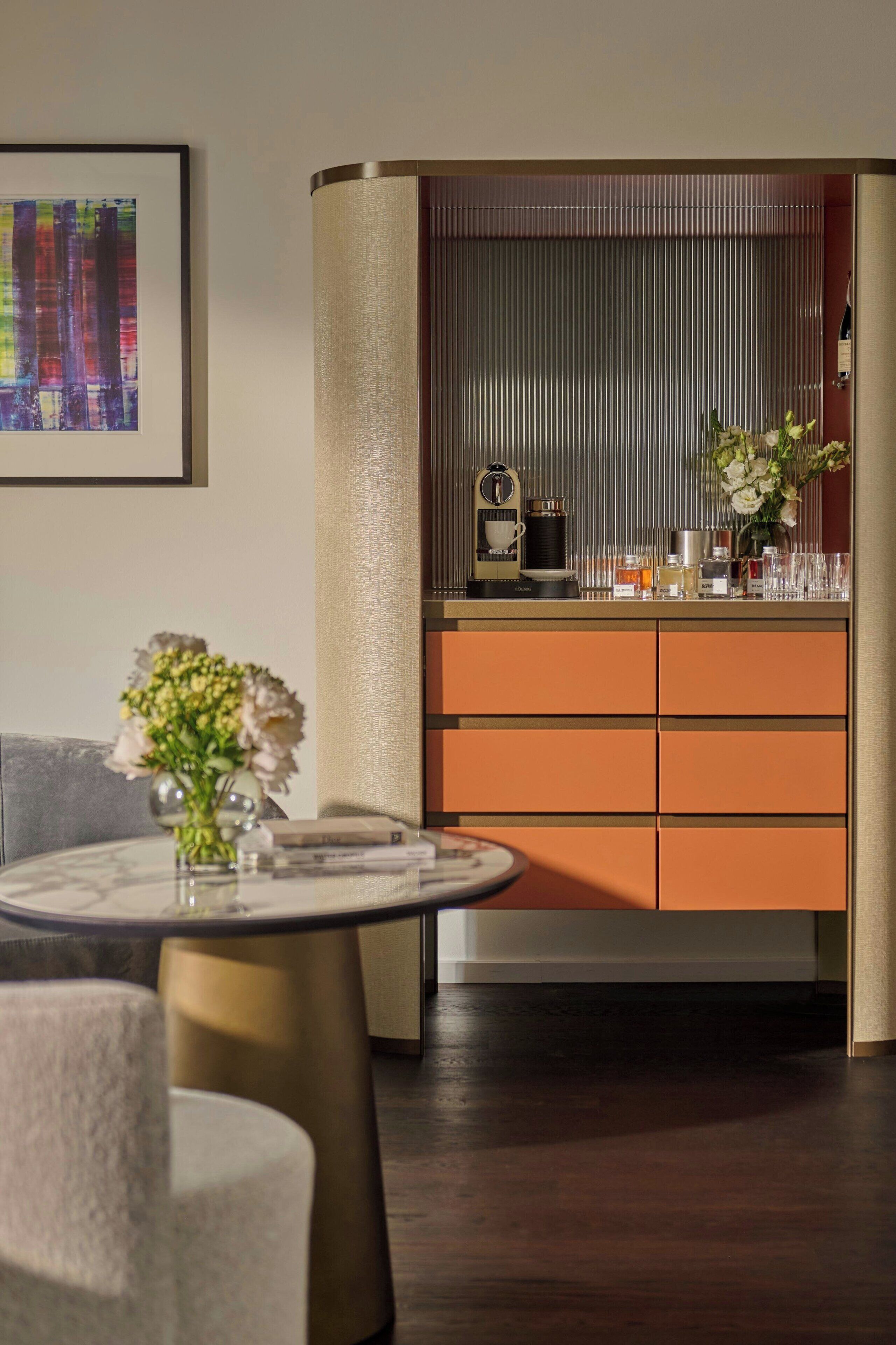 A modern interior with a round table, a sofa, and a cabinet with drawers.