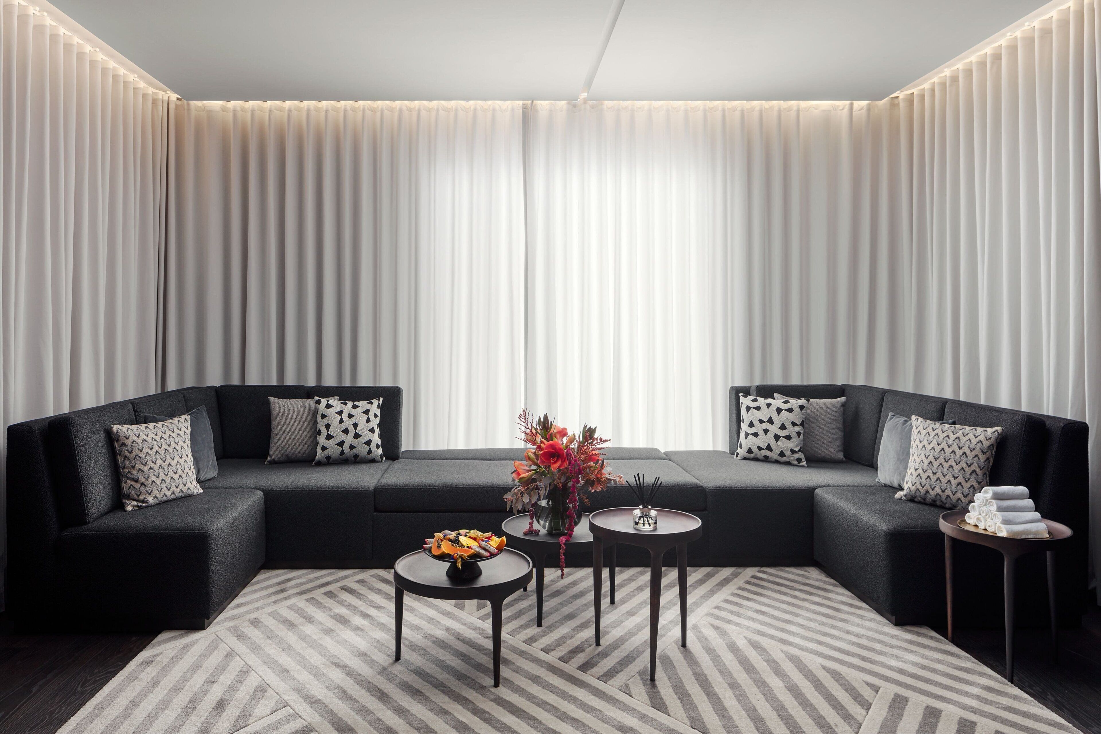 A modern living room with a sectional sofa, two side tables, and a decorative vase.