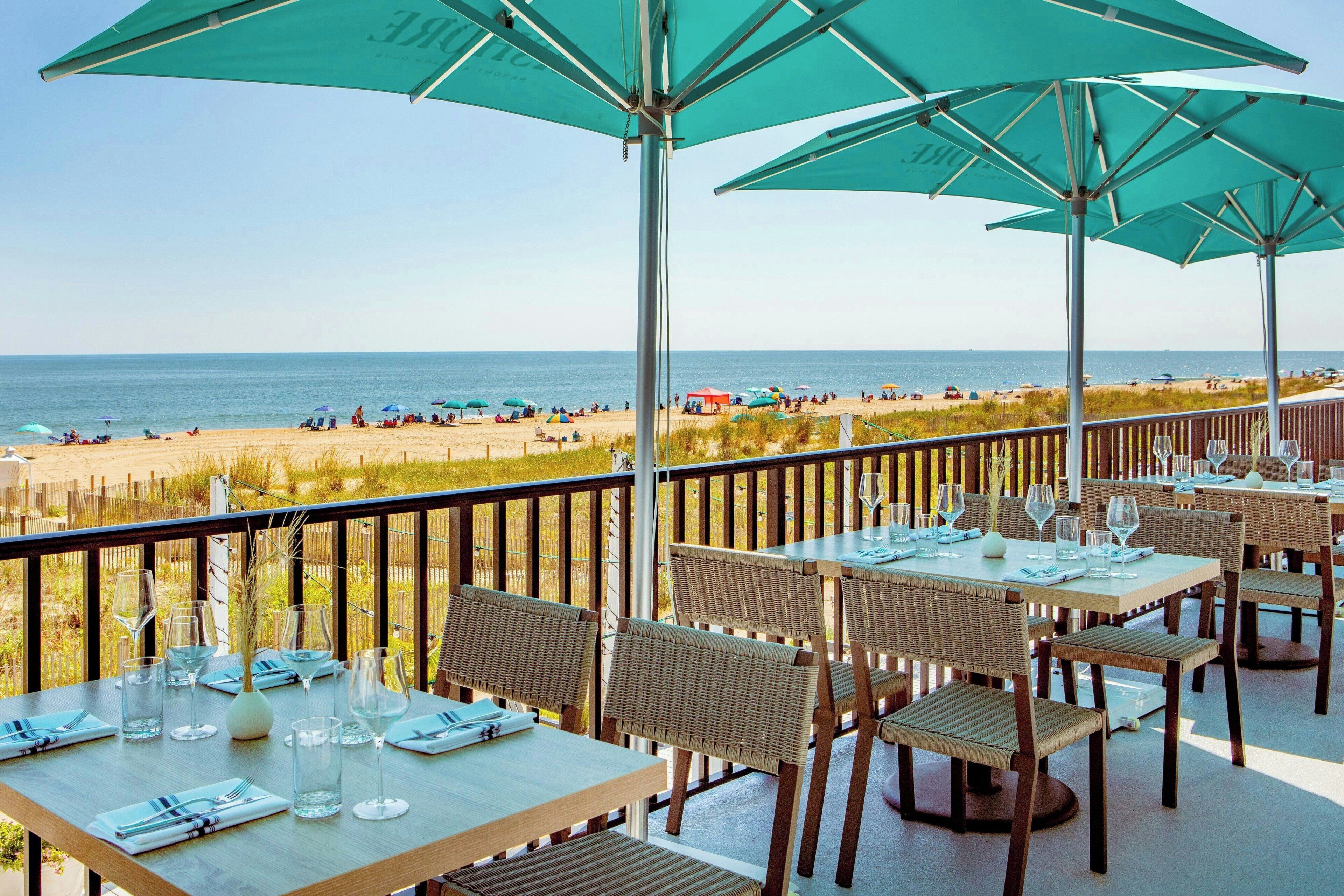 Una terraza con mesas y sillas, con vista a la playa.