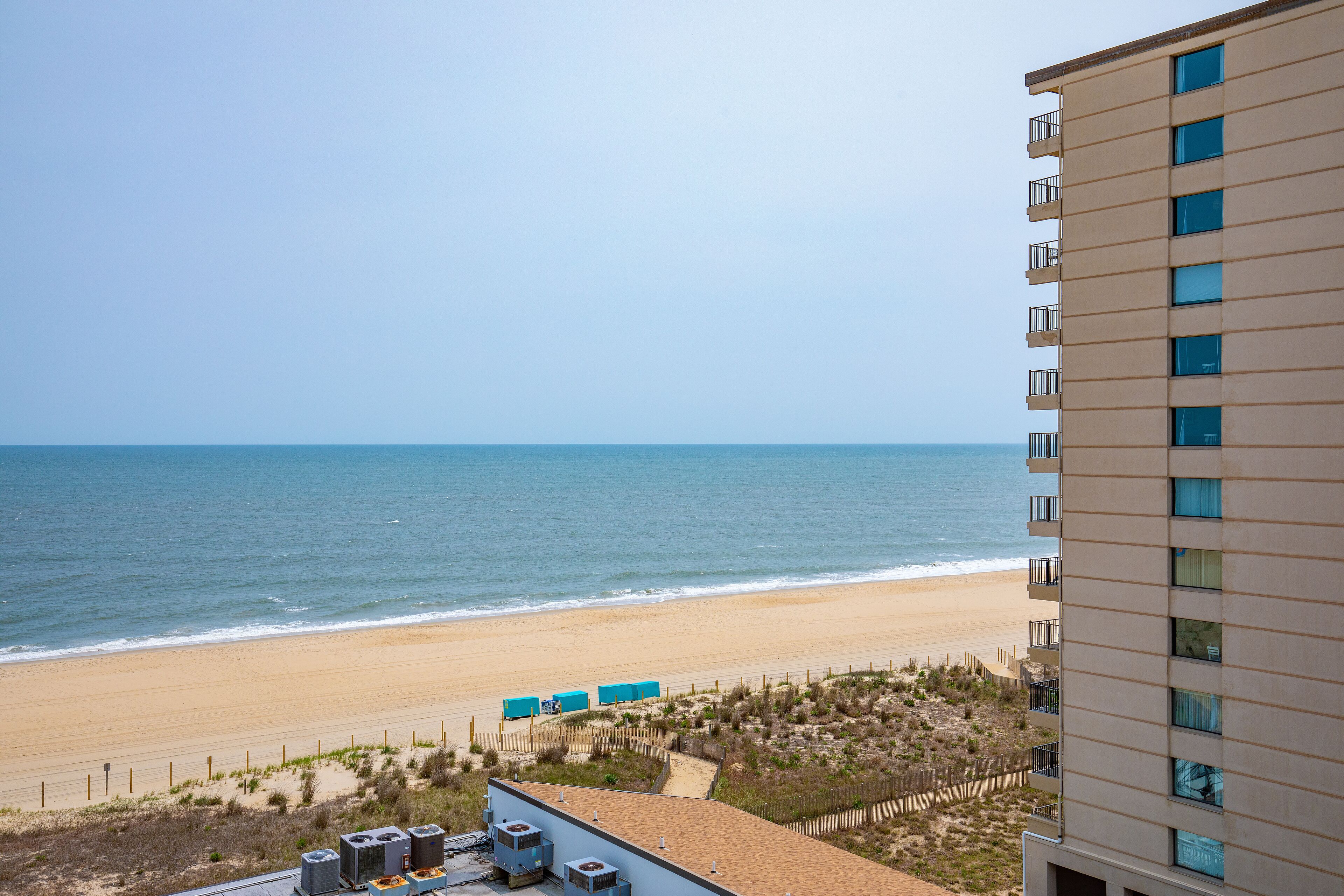 A high-rise hotel overlooking a beach with a clear view of the ocean.