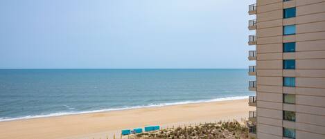 A high-rise hotel overlooking a beach with a clear view of the ocean.
