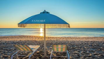 A beach umbrella labeled 'ASHORE' with two striped beach chairs.