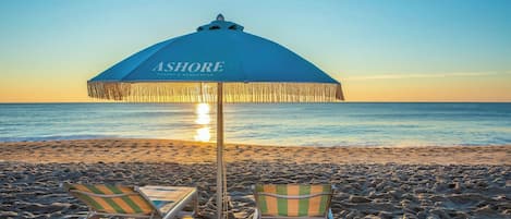 A beach umbrella labeled 'ASHORE' with two striped beach chairs.