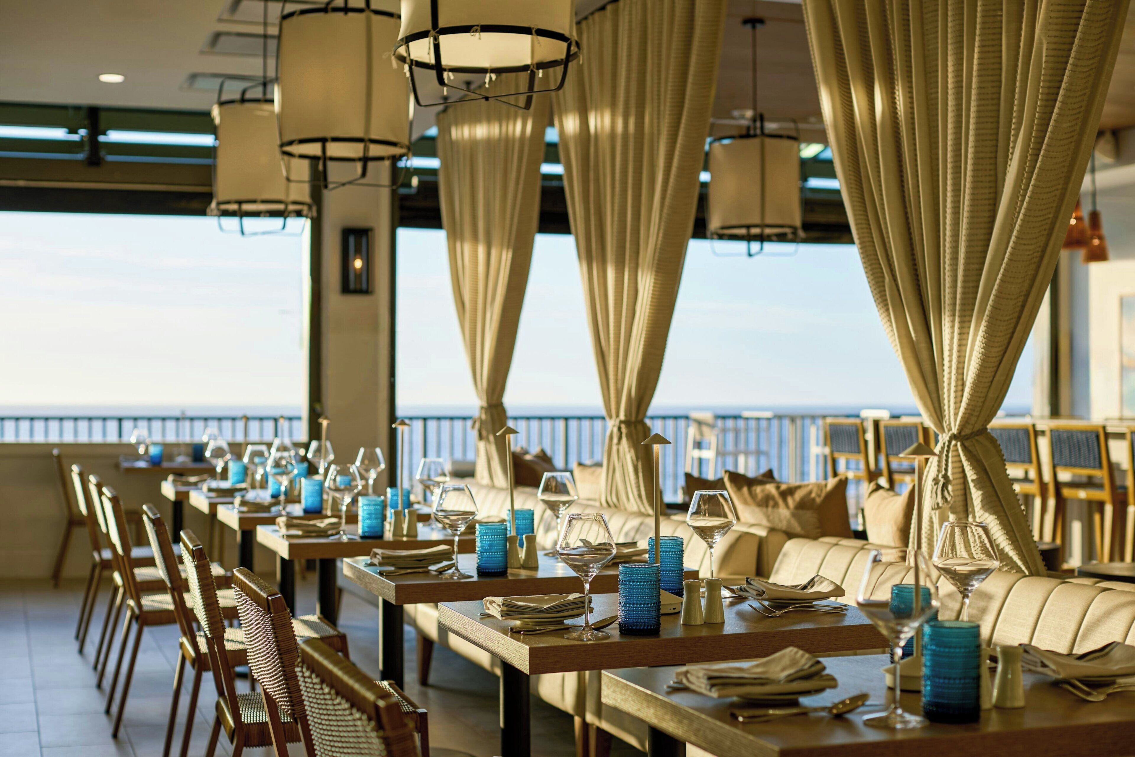 Un restaurante con mesas dispuestas para comer, con vista al mar.