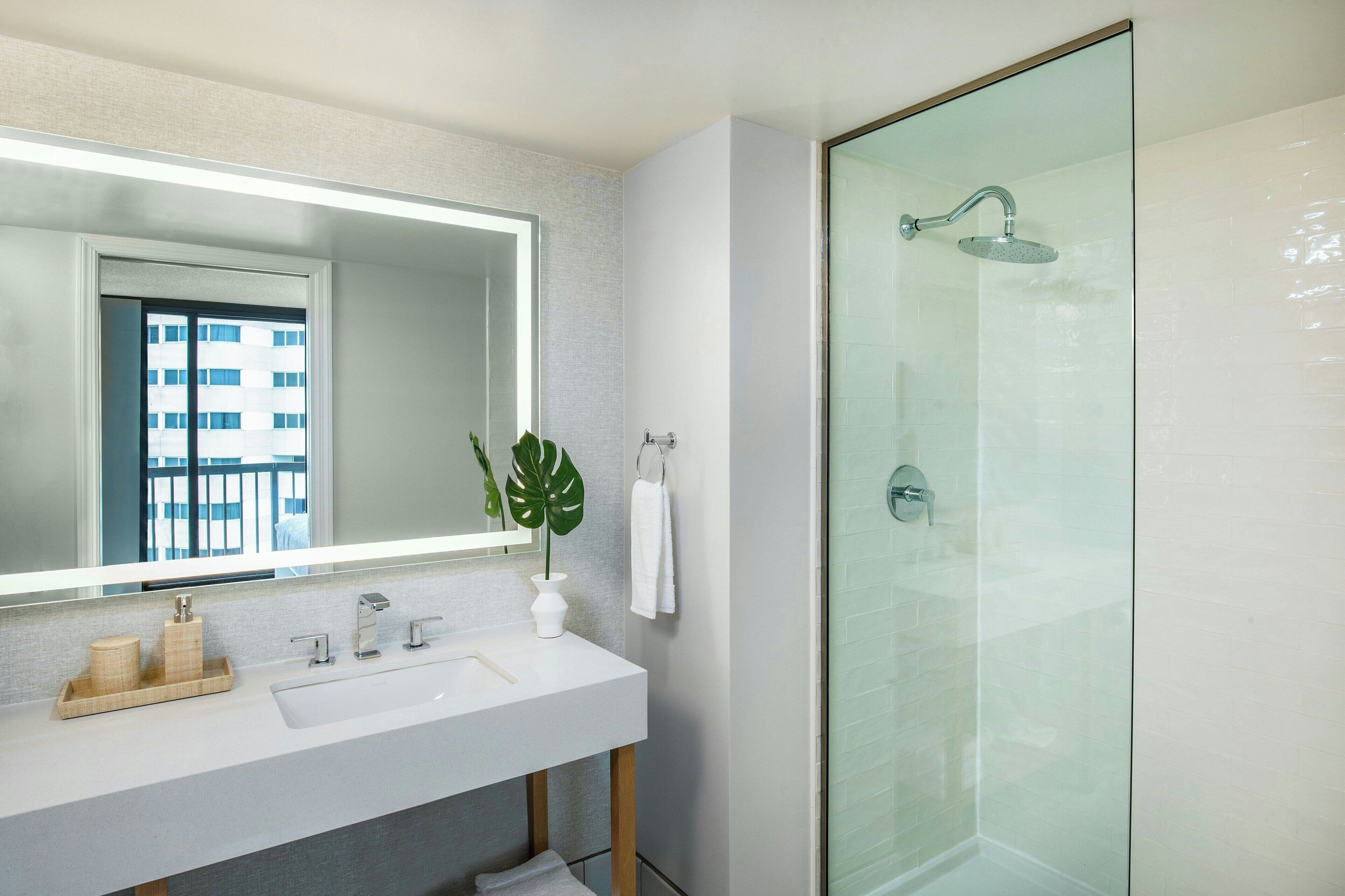 A modern bathroom with a glass-enclosed shower, a white sink, and a large mirror.