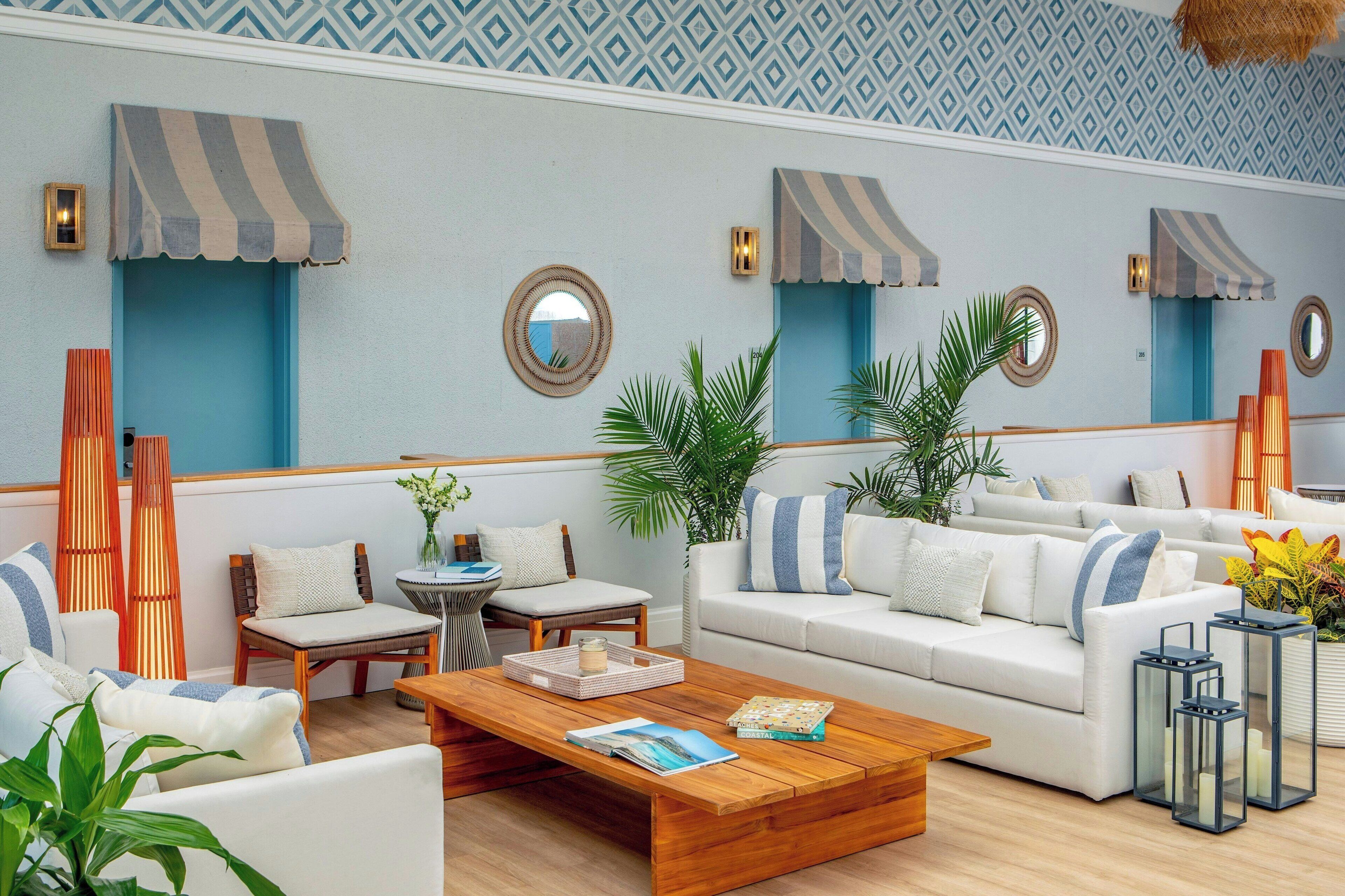 A modern lounge area with a sofa, chairs, a coffee table, and decorative plants.