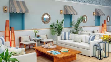 A modern lounge area with a sofa, chairs, a coffee table, and decorative plants.