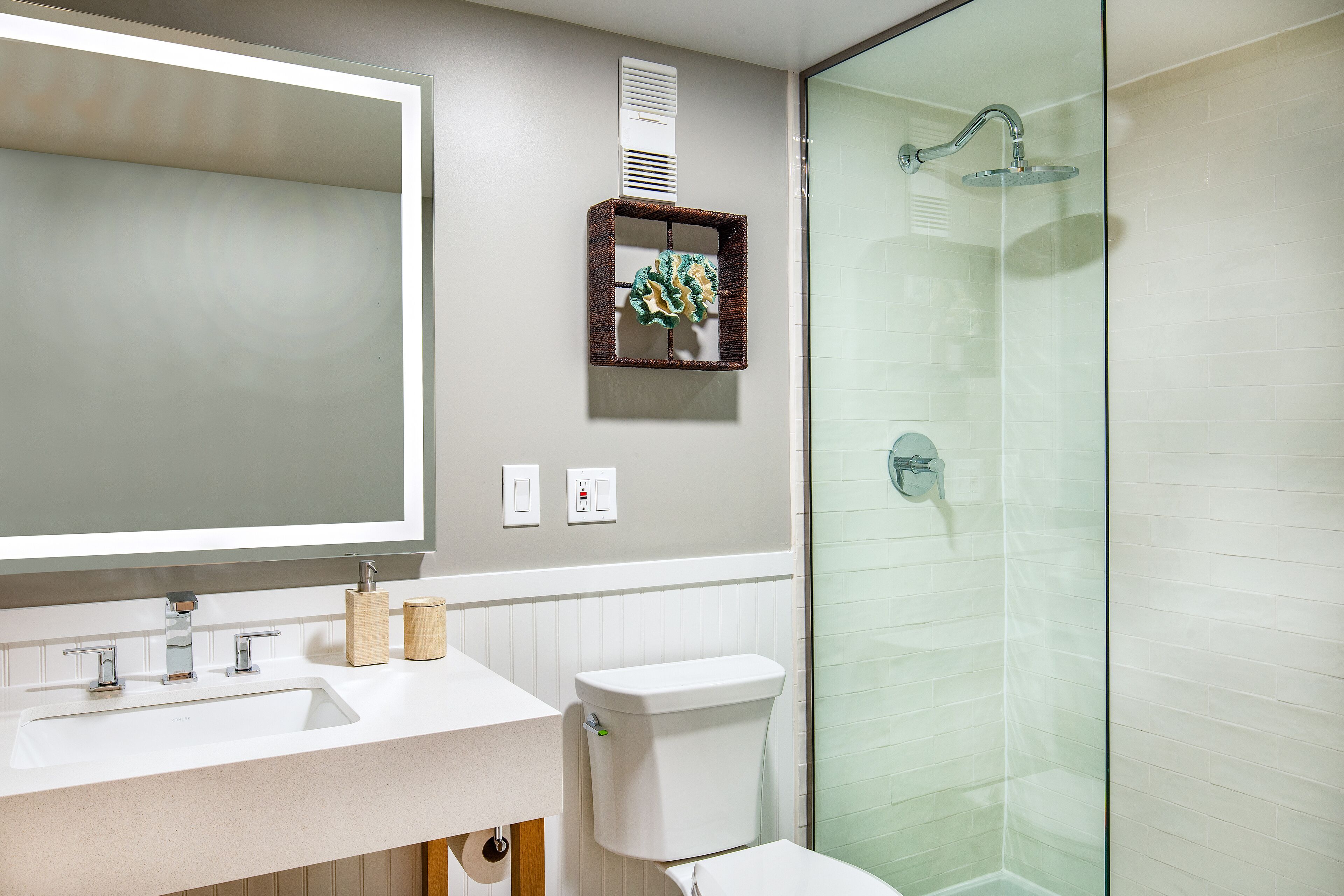 Une salle de bain avec un grand miroir, un lavabo, des toilettes et une douche à parois de verre.