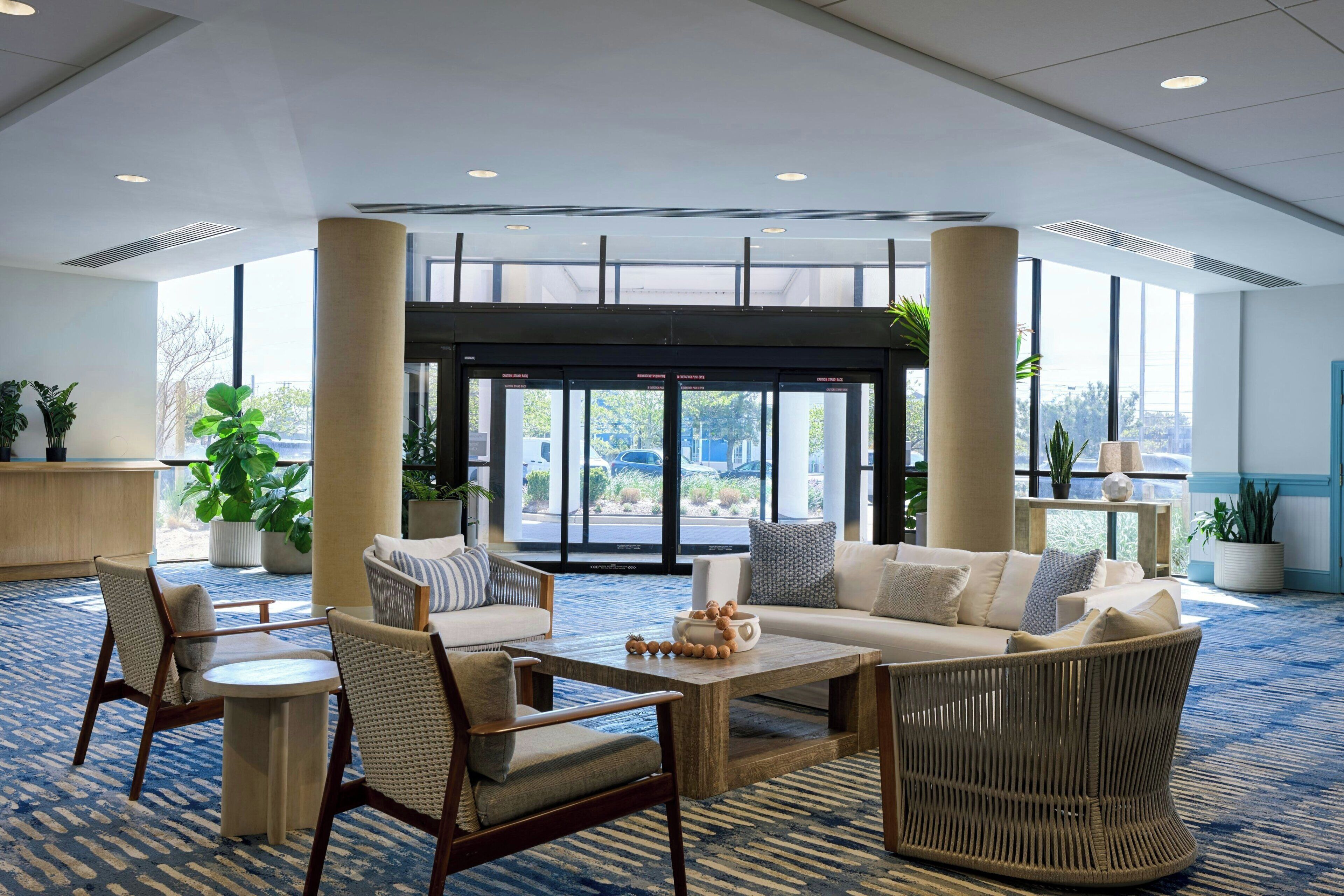 A lobby with a seating area, large windows, and a view of the outside.
