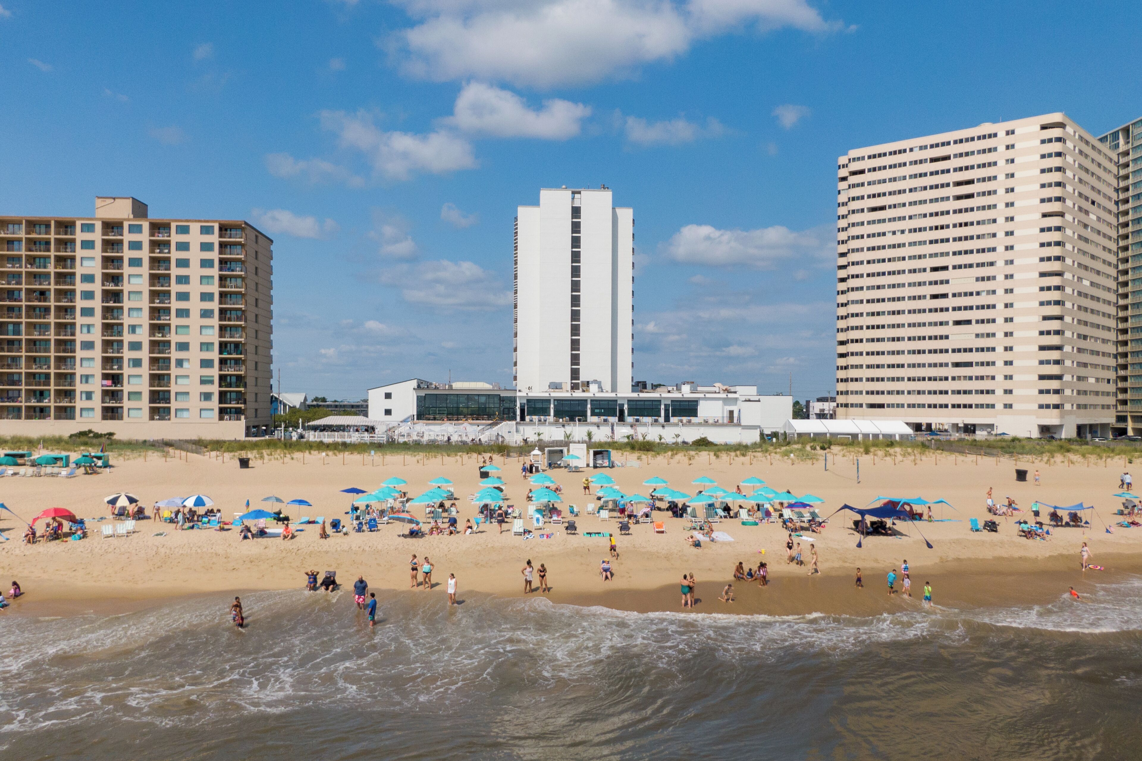 A beach with a hotel and high-rise buildings in the background.