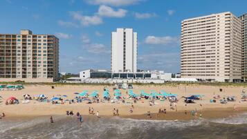 A beach with a hotel and high-rise buildings in the background.