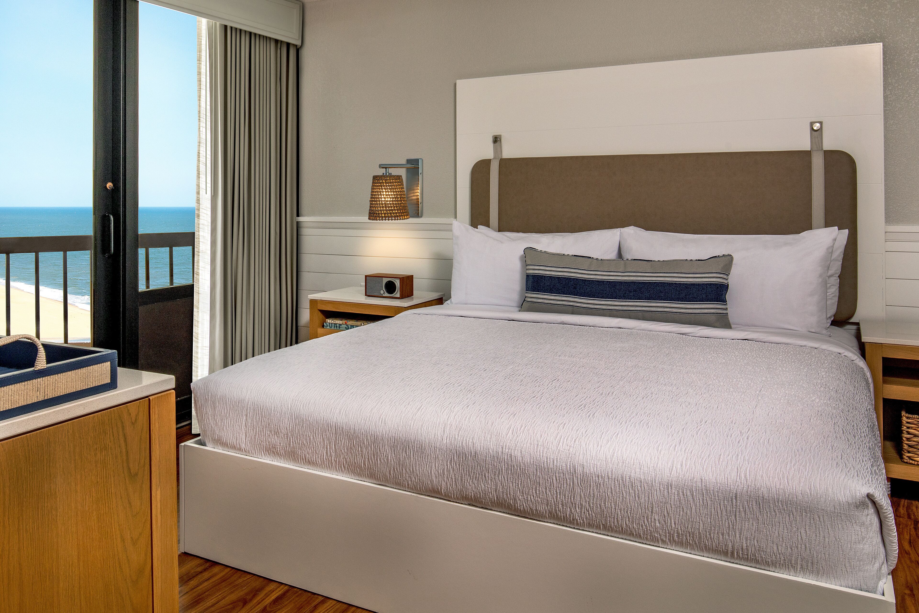 Una camera d'albergo con un letto grande, un comodino con una lampada e vista sull'oceano.