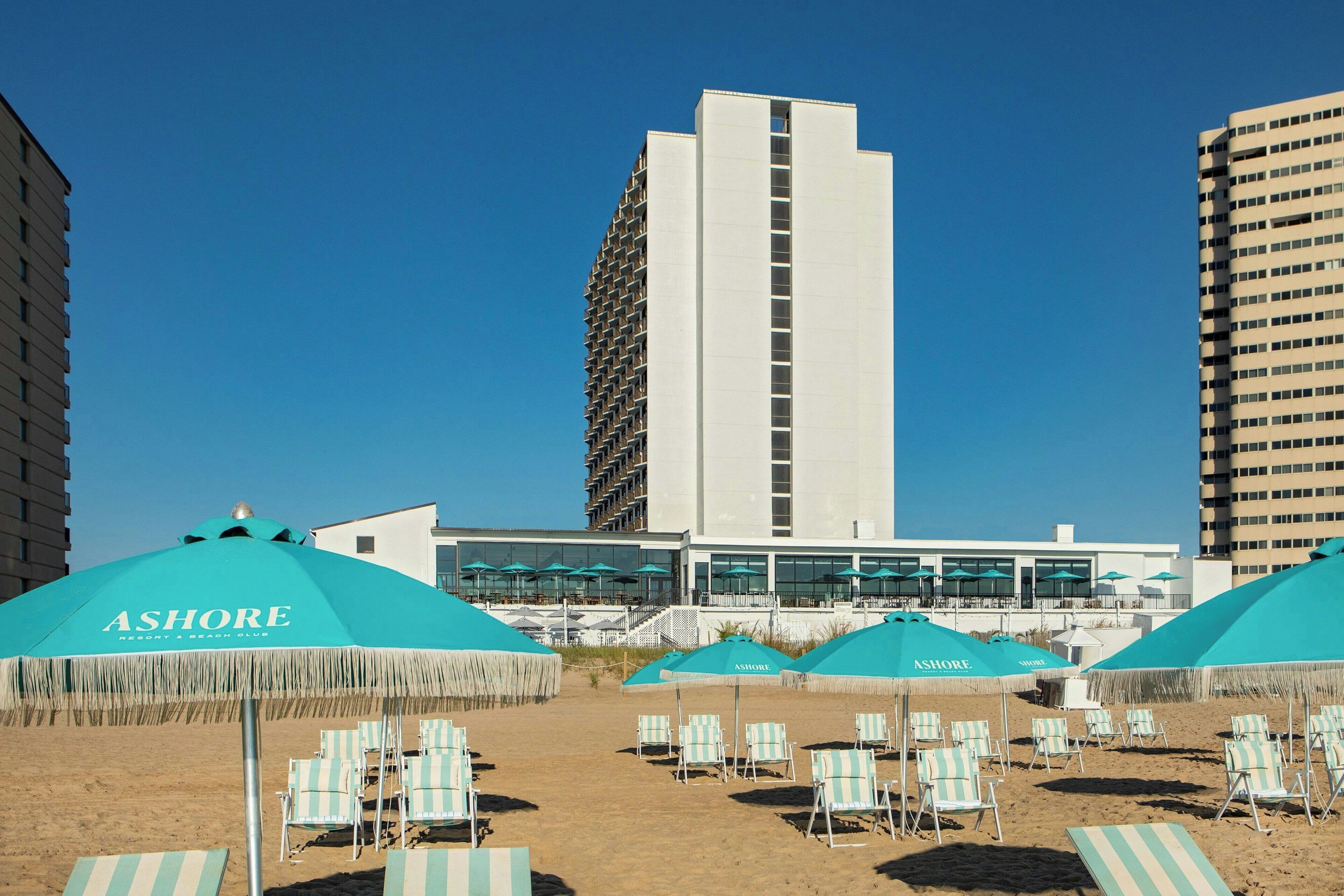 A beach with sun umbrellas labeled 'ASHORE' and lounge chairs.