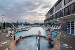 Una piscina con sillas de descanso y un edificio con balcones.