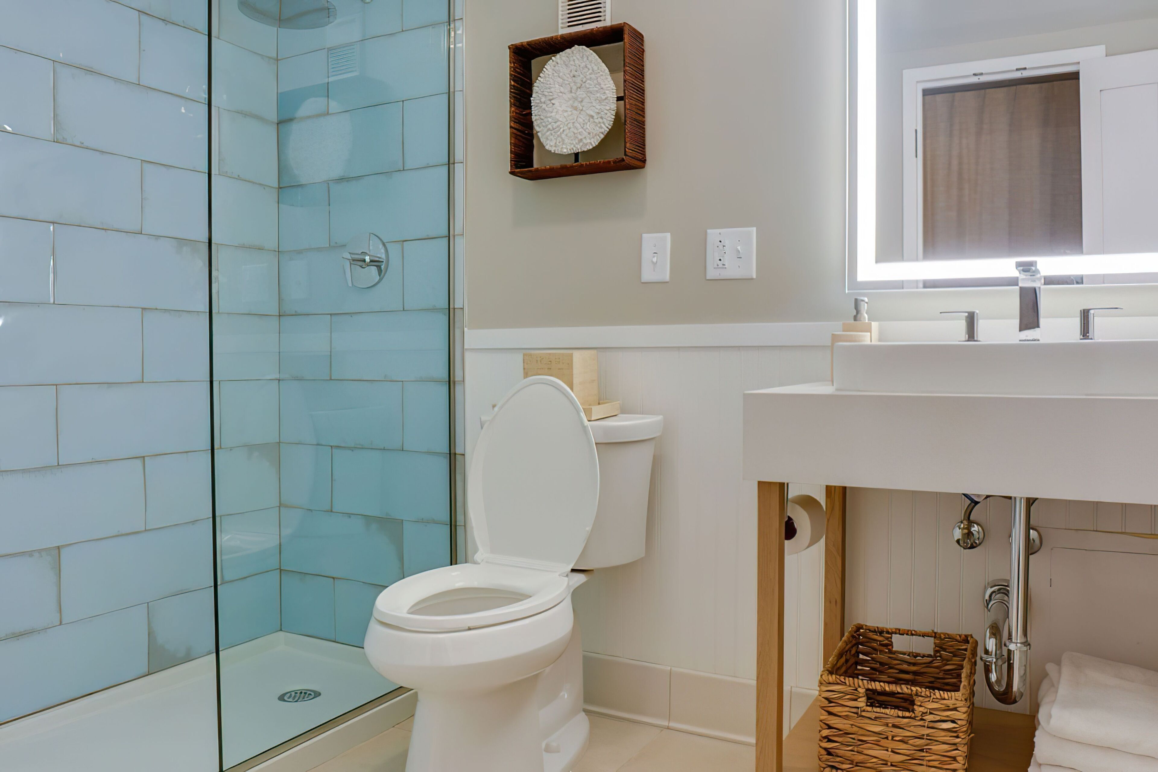A modern bathroom with a glass shower enclosure, a white toilet, and a wooden vanity with a mirror above the sink.