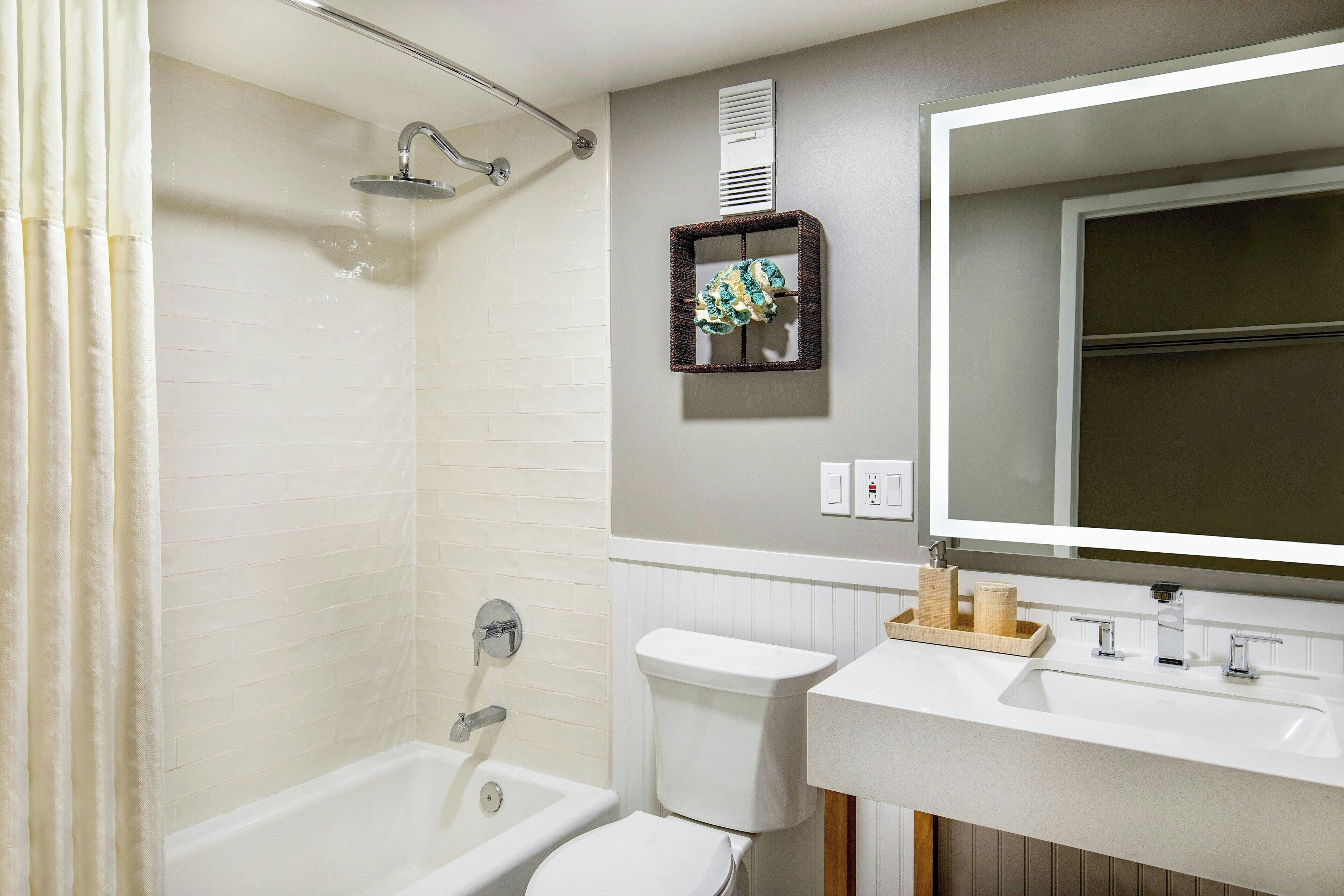 A bathroom with a shower, toilet, sink, and mirror.