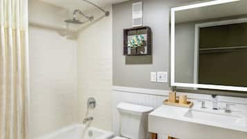 A bathroom with a shower, toilet, sink, and mirror.