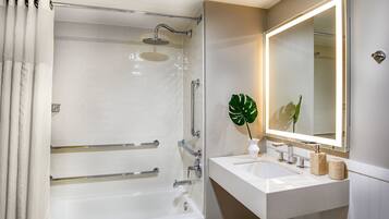 A modern bathroom with a bathtub, shower, and a vanity with a mirror.