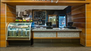 Un café moderne avec un tableau affichant le menu, un présentoir de fruits et une machine à café.