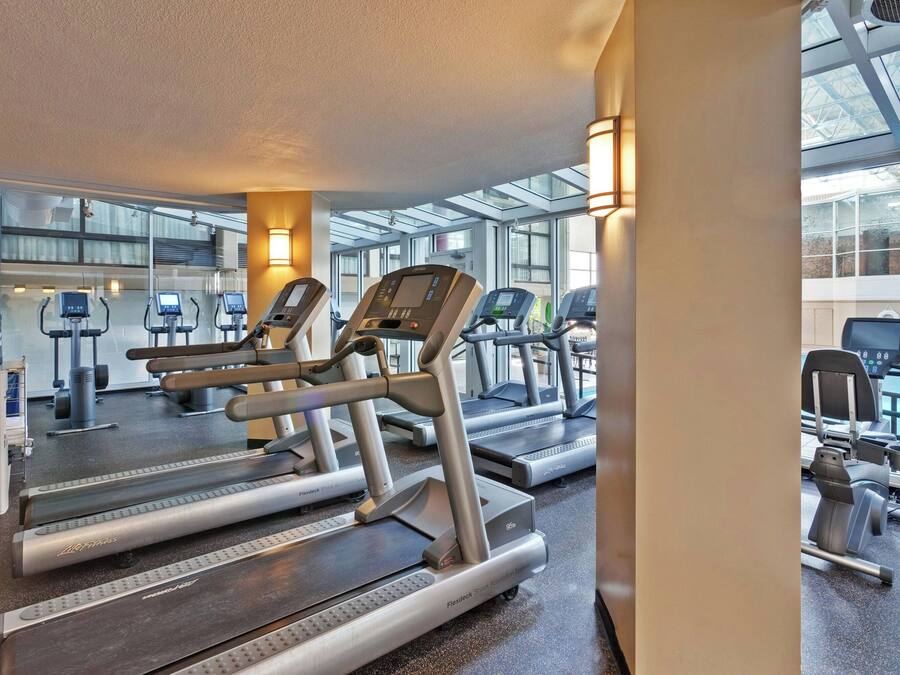 A gym with treadmills, exercise bikes, and a pool area.