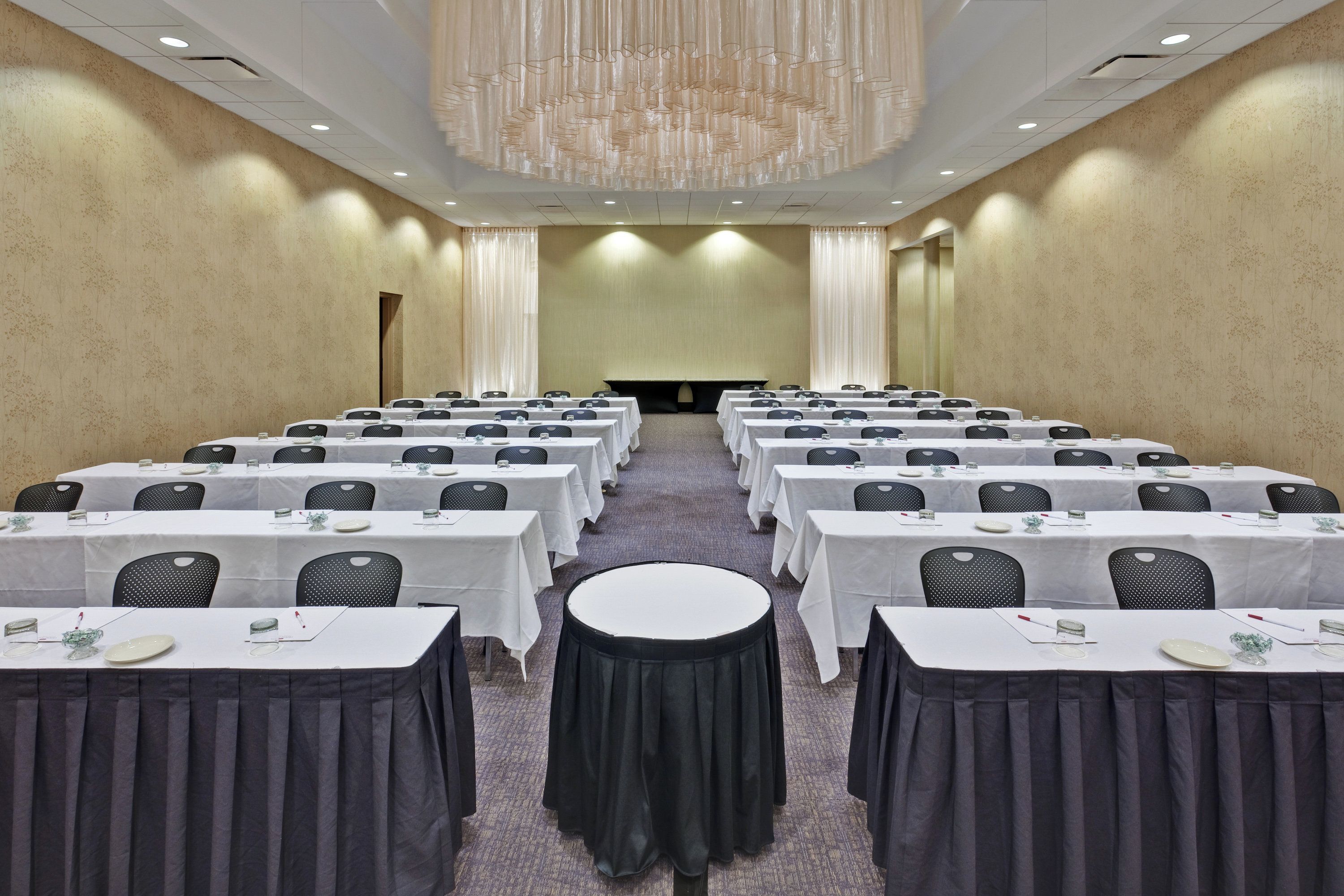 A conference room with rows of tables, chairs, and a large chandelier.