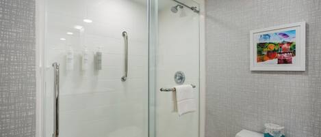 A modern bathroom with a glass shower enclosure, a toilet, and a framed picture on the wall.