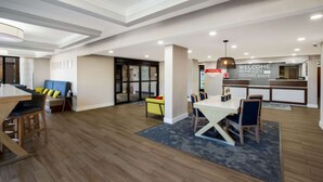A spacious living area with a dining table, a sofa, and a kitchen area with a welcome sign. - Hampton Inn by Hilton Philadelphia / Willow Grove (Willow Grove)