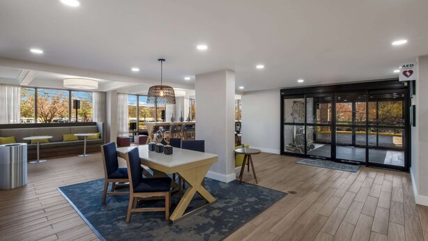 A modern interior with a dining area, seating, and a glass door entrance. - Hampton Inn by Hilton Philadelphia / Willow Grove (Willow Grove)
