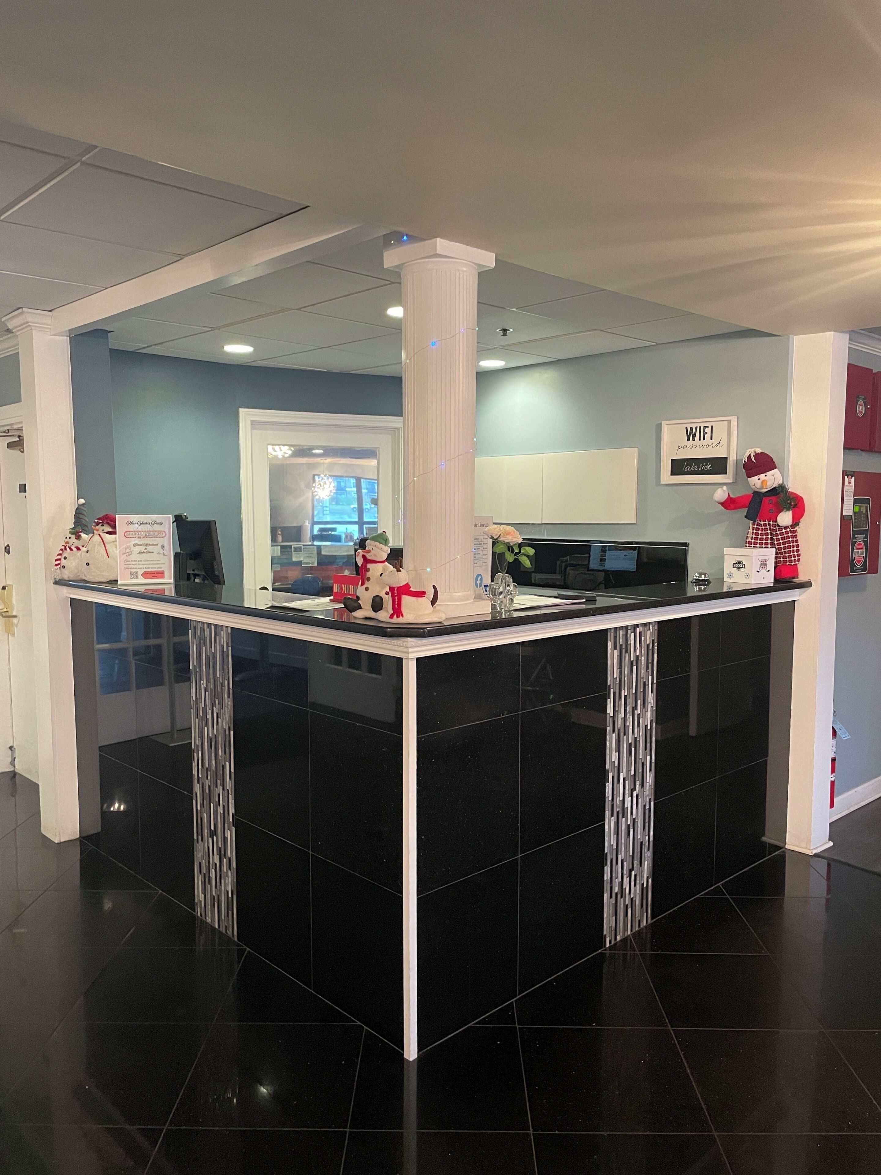 A reception area with a black and white tiled floor, a white reception desk, and a column with string lights.
