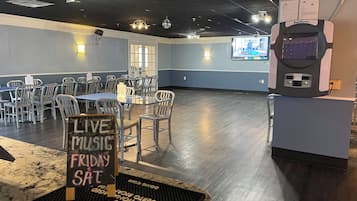 A spacious room with tables and chairs, a sign for live music on Fridays, and a jukebox.