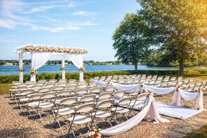 An outdoor wedding setup with a white arch and chairs arranged for guests. - Lakeside Inn (Wakefield)
