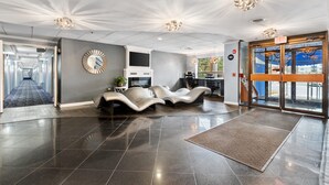 A modern lobby with a reception desk, seating area, and a large mirror on the wall.