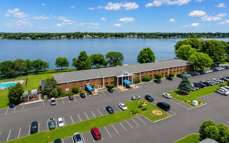 A hotel with a swimming pool, parking lot, and a view of a lake.