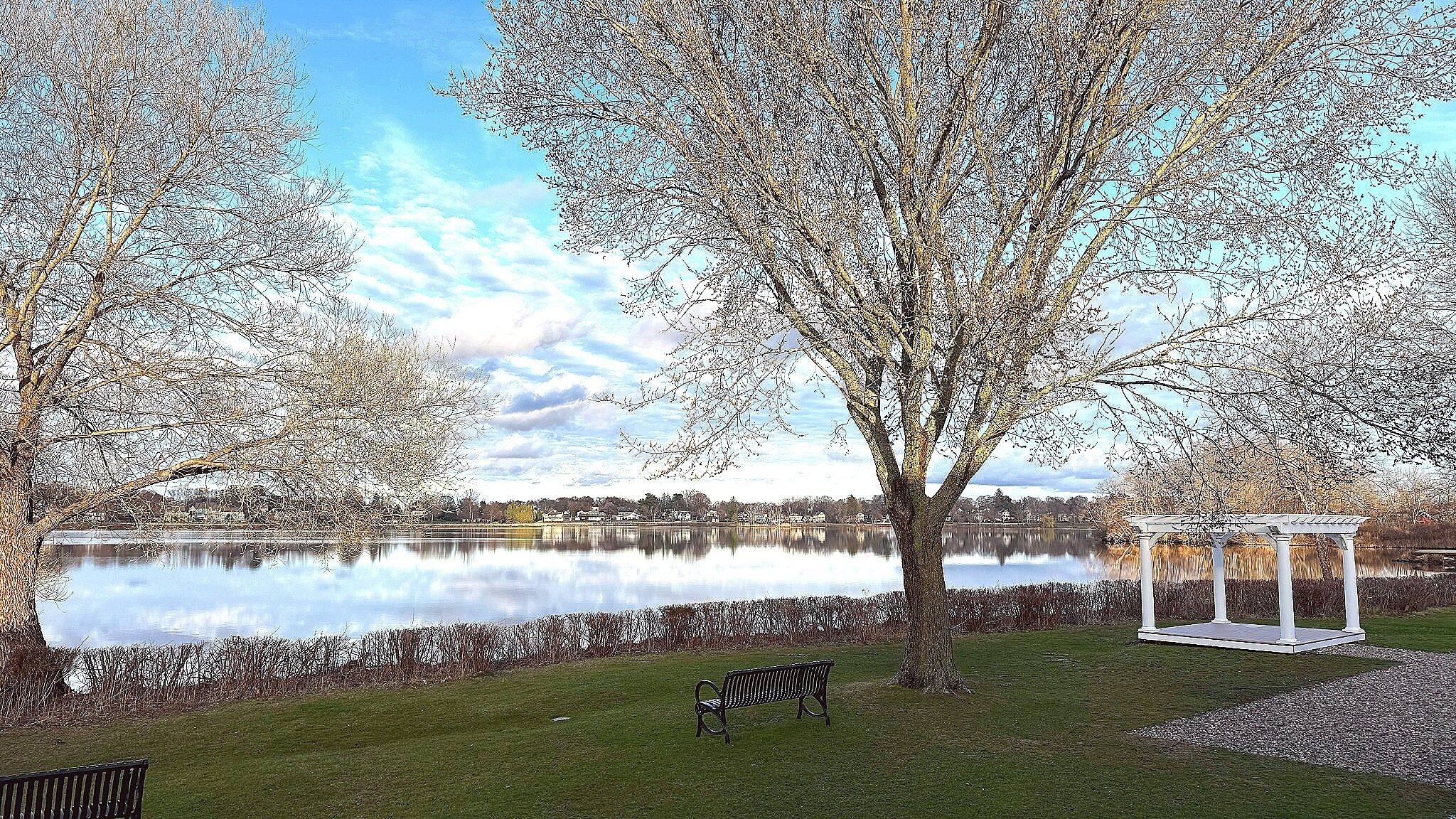 A park with a lake, benches, and a gazebo.