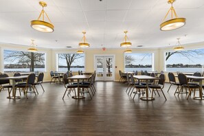A spacious dining area with multiple tables and chairs, large windows with a view, and a door marked 'EXIT'. - Lakeside Inn (Wakefield)