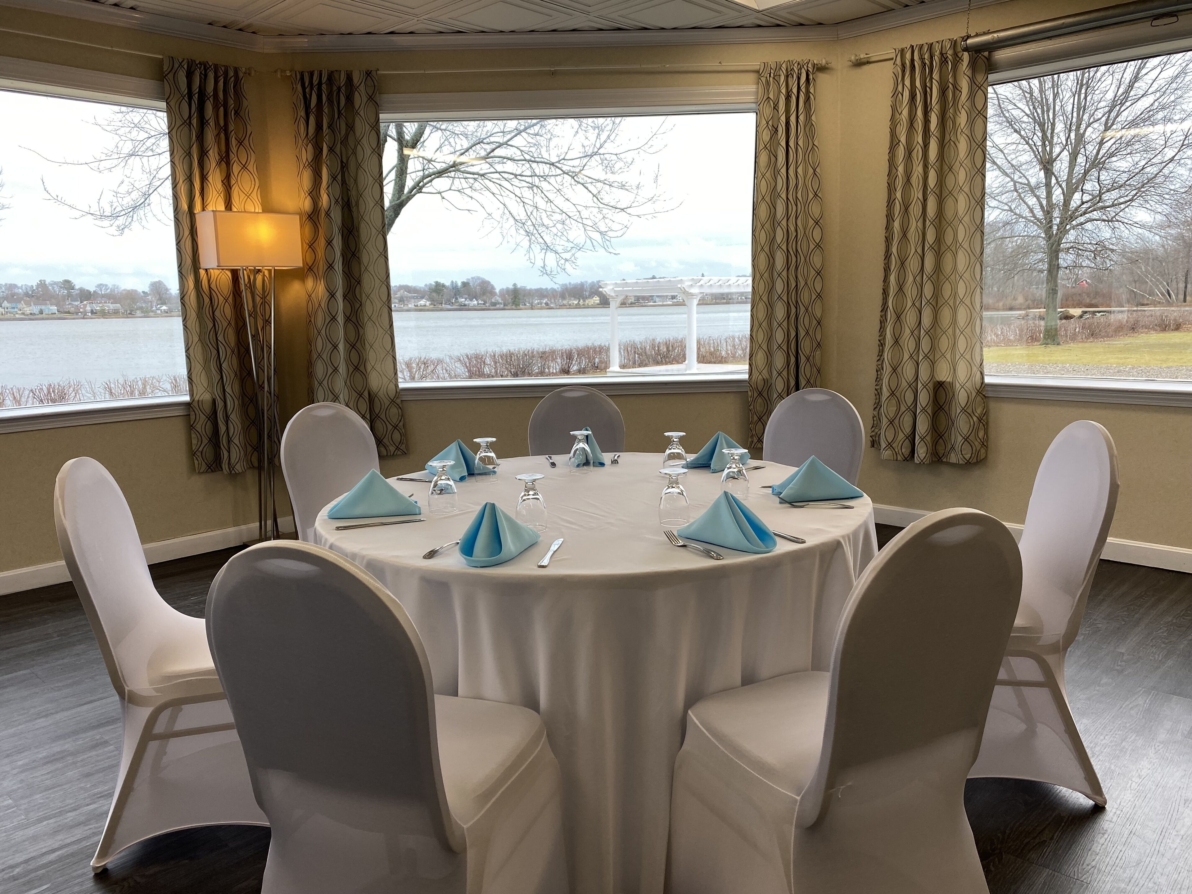 Une salle de conférence équipée d’une table ronde, de chaises et offrant une vue sur un plan d’eau grâce à de grandes fenêtres.