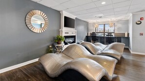 A modern living room with a unique curved sofa, a large mirror, and a kitchen area with a bar.
