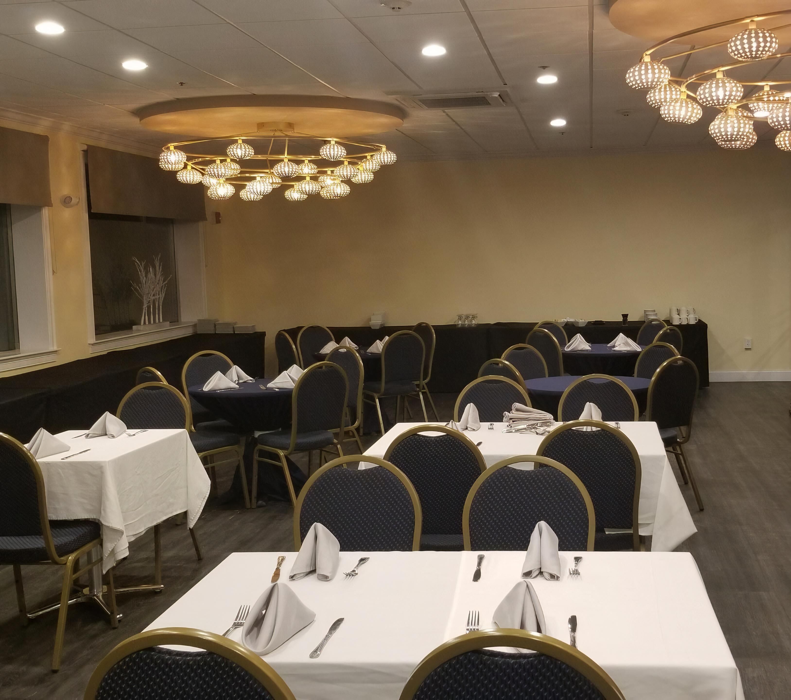A conference room with round tables, chairs, and a chandelier.