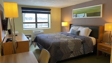 A hotel room with a bed, bedside lamps, a desk with a telephone, a chair, a window with a view, and a painting on the wall.