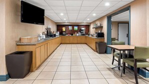 Un área de cocina moderna con televisor de pantalla plana, cafetera y refrigerador.