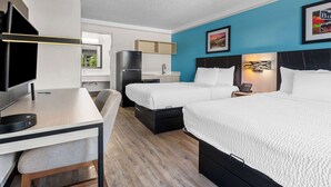 Una habitación de hotel con dos camas, un escritorio, un televisor y una kitchenette.