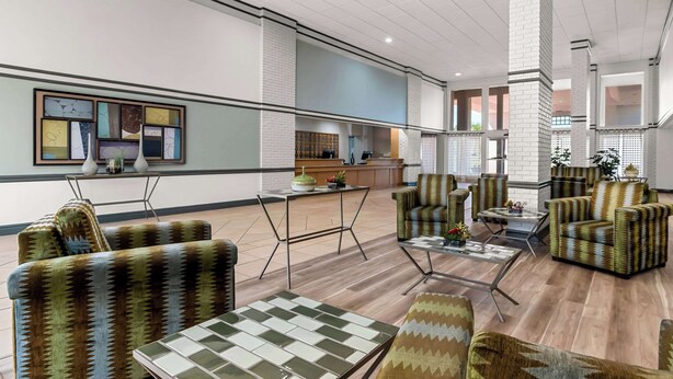 Un vestíbulo amplio con muebles modernos, una recepción y vistas al área de la cocina.