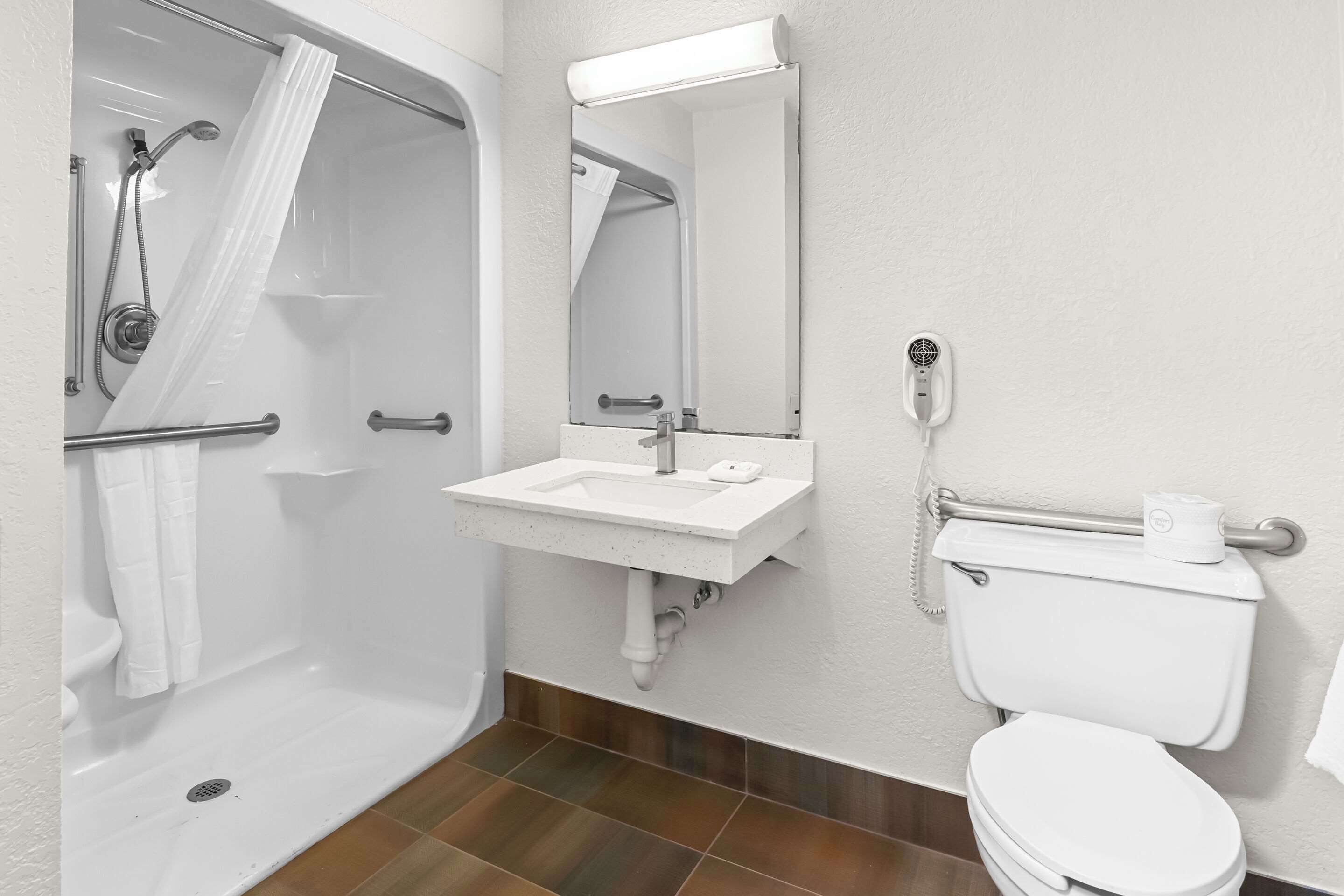 Un baño con ducha, lavamanos, inodoro y espejo.