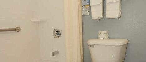 A bathroom with a bathtub, toilet, and a towel rack with two towels.
