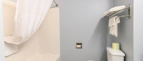 Un baño con bañera, inodoro y cortina de ducha.