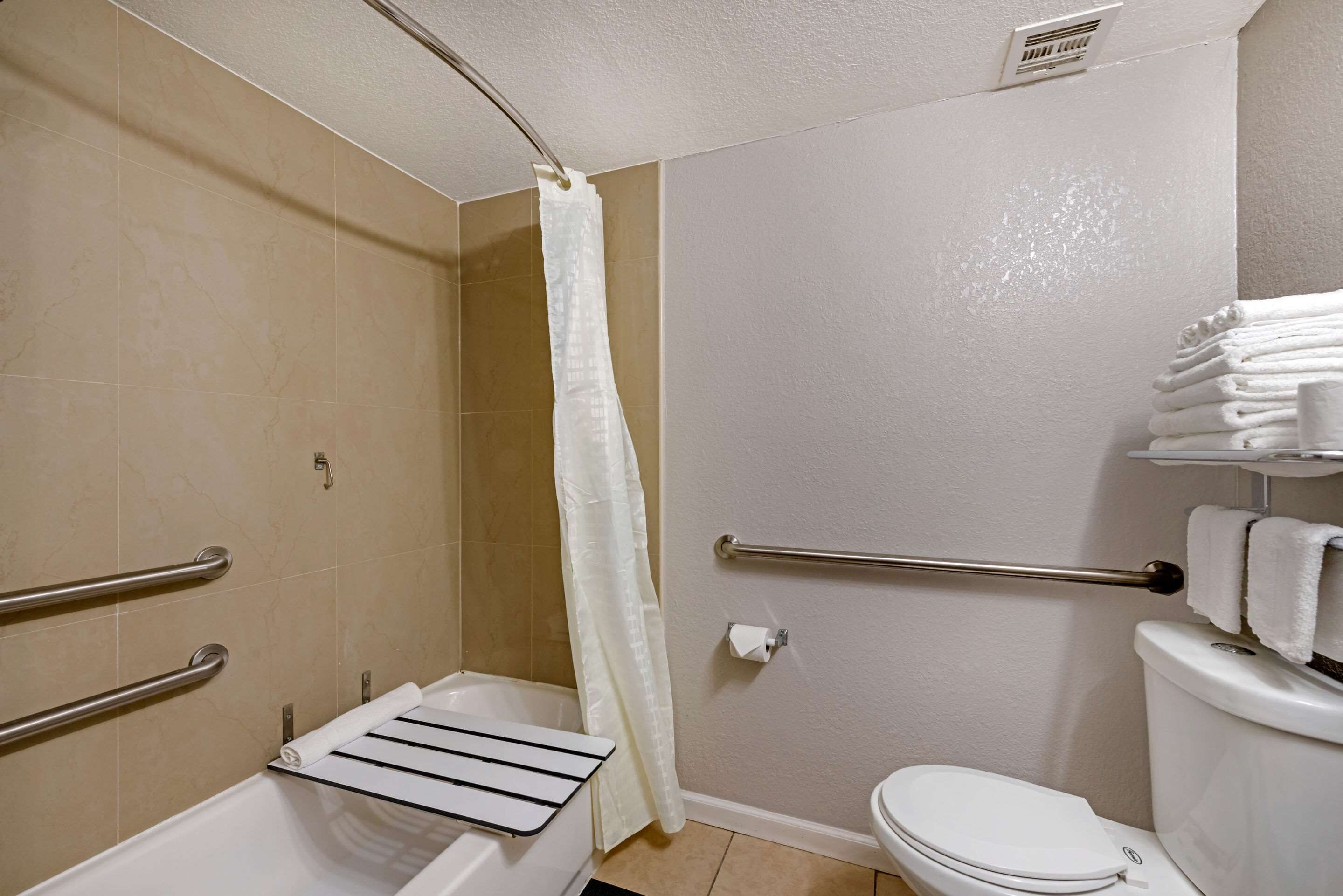 A bathroom with a bathtub, a toilet, a shower curtain, and a towel rack.