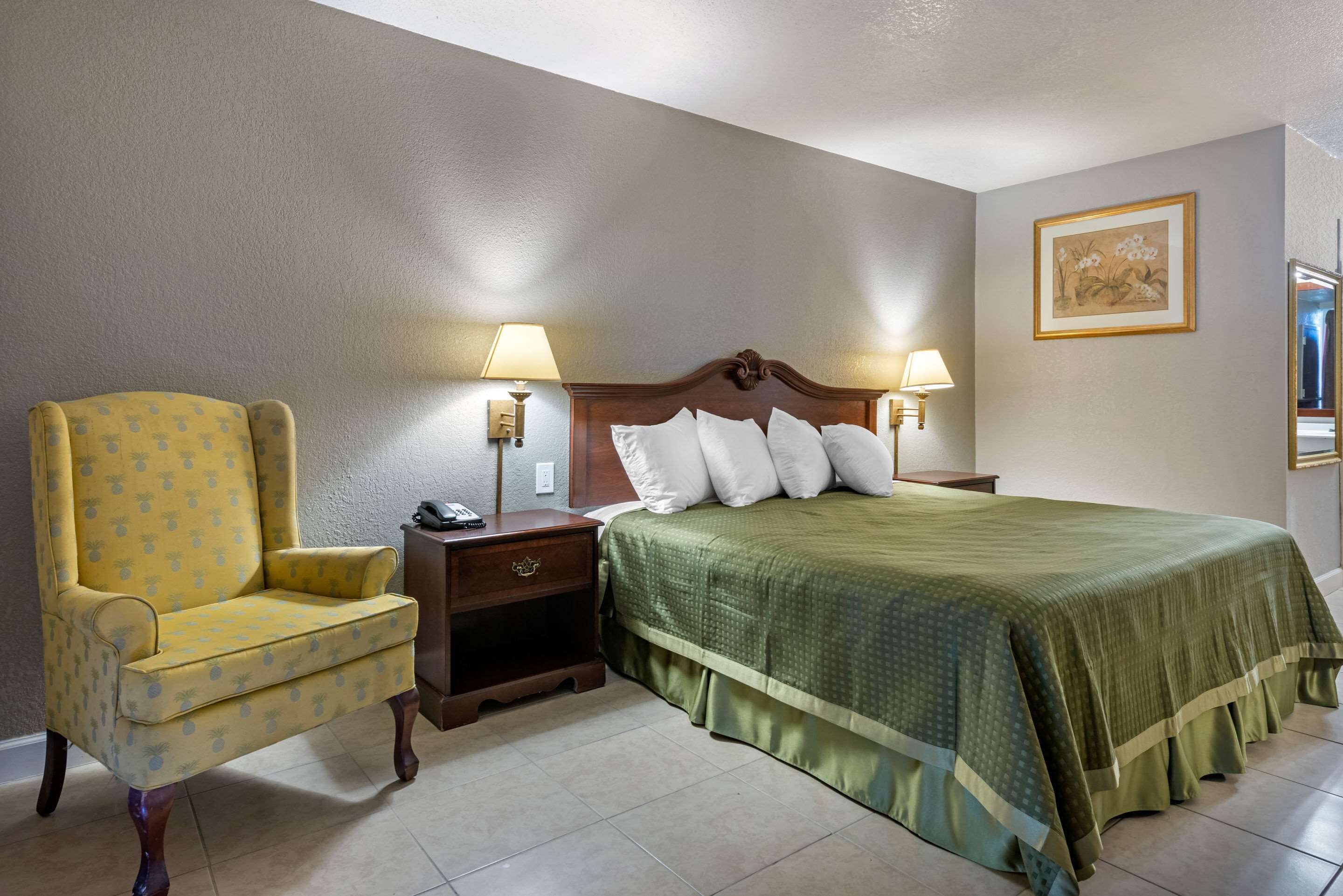 Een hotelkamer met een bed, twee nachtkastjes, een stoel en een wandlamp.
