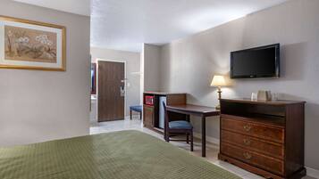 A hotel room with a bed, a desk with a chair, a television, and a dresser.