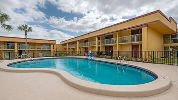 Un hotel con piscina, varios balcones y cielo despejado.