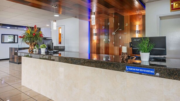 A hotel reception area with a marble counter, wooden ceiling, and a clock. - Rodeway Inn Clermont North (Clermont)